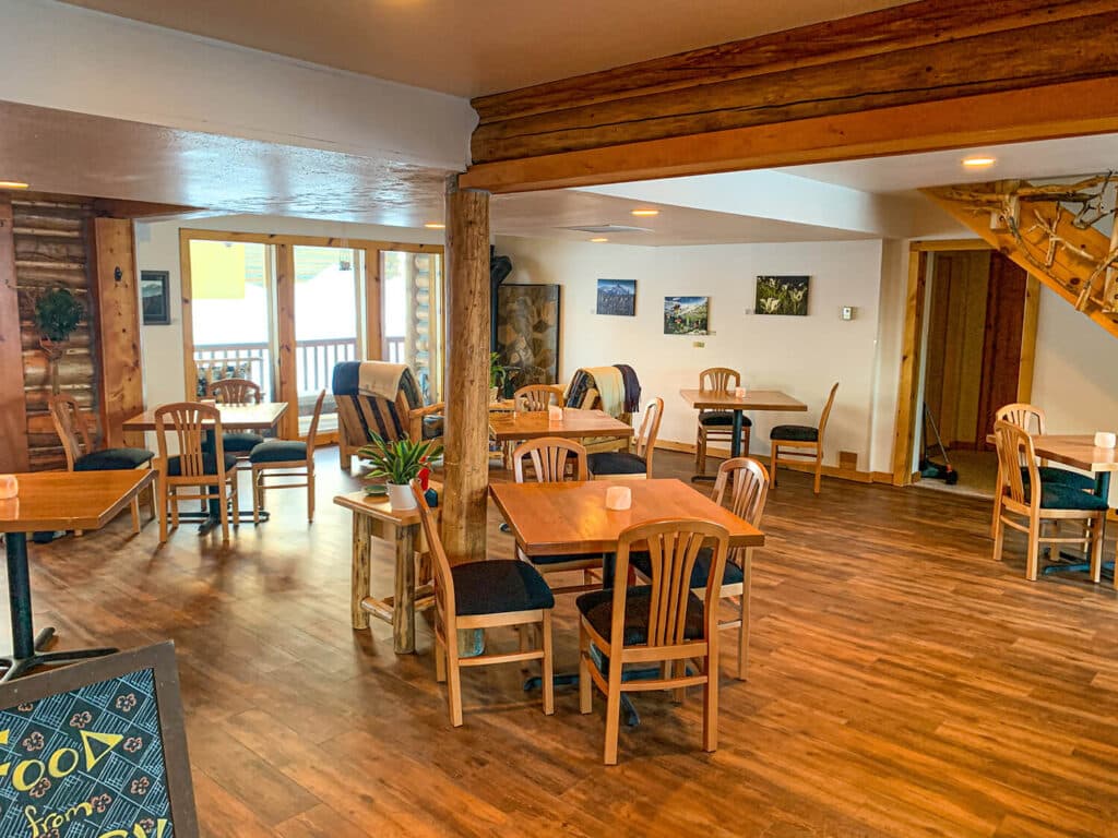 A cozy dining area featuring wooden tables and chairs, with a warm ambiance and natural light.
